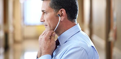 Lekar koji stavlja Littmann stetoskop pravilno sa olivama okrenutim prema napred.
