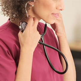 Medicinska sestra koja stavlja olive njenog 3M Littmann Classic III stetoskopa u uši.